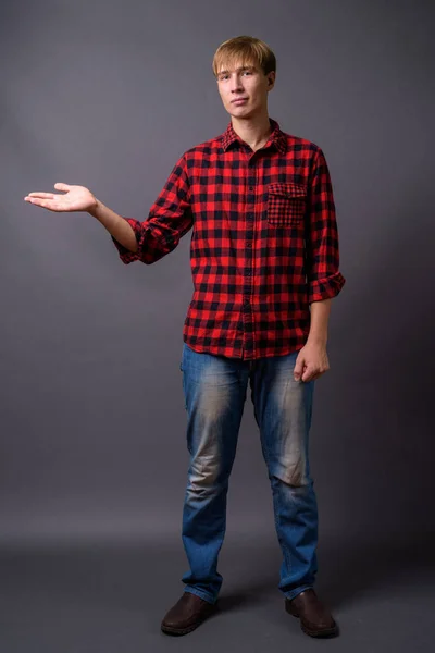 Full length portrait of young man standing against gray background — Stock Photo, Image