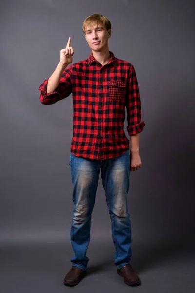 Full length portrait of young man standing against gray background — Stock Photo, Image