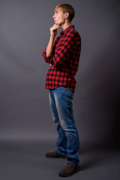 Full length portrait of young man standing against gray background — Stock Photo, Image