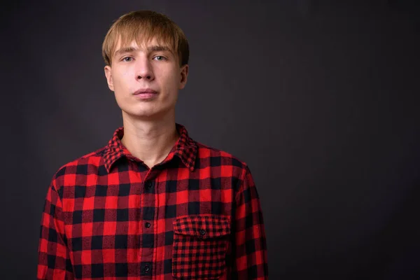 Young handsome man with blond hair against gray background — Stock Photo, Image