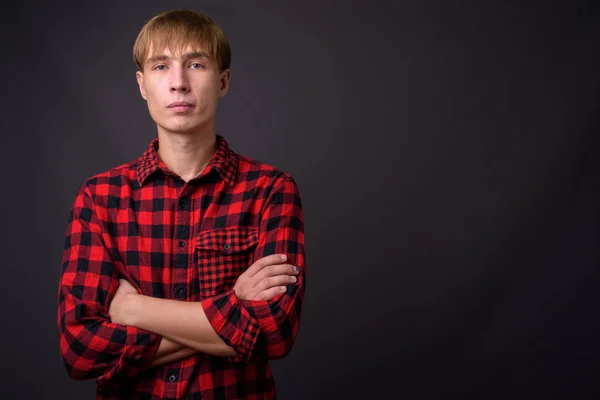 Junger schöner Mann mit blonden Haaren vor grauem Hintergrund — Stockfoto