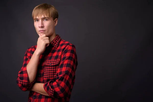 Young handsome man with blond hair against gray background — Stock Photo, Image