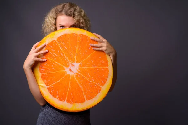 Giovane bella donna che tiene grande fetta di frutta arancione — Foto Stock