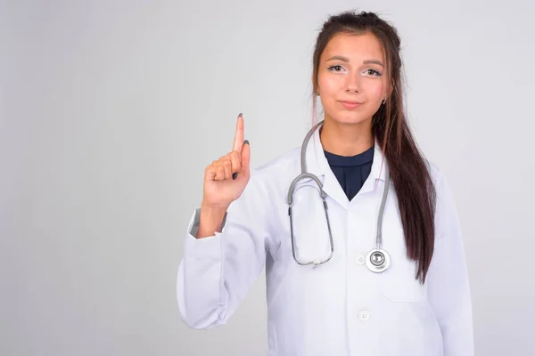 Молода красива жінка-лікар вказує пальцем вгору — стокове фото