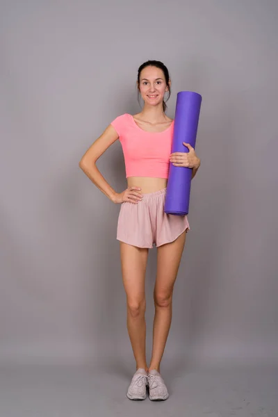 Jeune belle femme prête pour la salle de gym tenant tapis de yoga — Photo