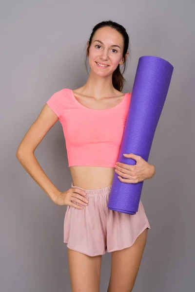 Молодая красивая женщина готова к спортзалу проведение коврик для йоги — стоковое фото