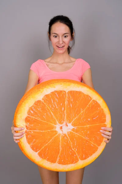 Giovane bella donna pronta per la palestra con una grande fetta di frutta arancione — Foto Stock