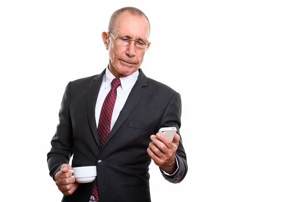 Studioaufnahme eines leitenden Geschäftsmannes mit Kaffeetasse während der Benutzung — Stockfoto