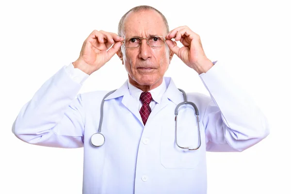 Студийный снимок пожилого врача, держащего очки с обеими руками — стоковое фото
