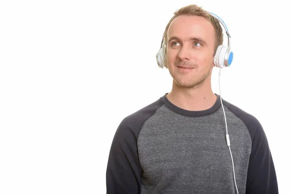 Komea valkoihoinen mies kuuntelee musiikkia miettiessään — kuvapankkivalokuva