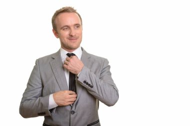 Beyaz arka plan karşı izole kravatını sabitleme yakışıklı beyaz işadamı