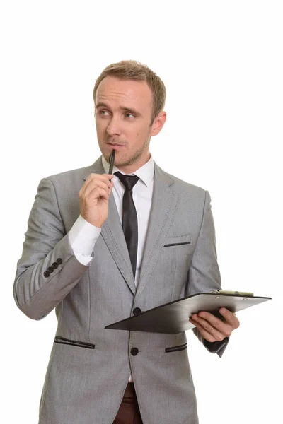 Guapo caucásico hombre de negocios celebración de pluma y portapapeles mientras t — Foto de Stock