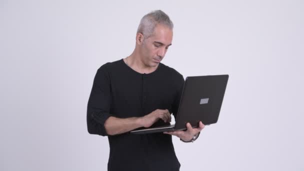 Счастливый красивый персидский мужчина думает во время использования ноутбука — стоковое видео
