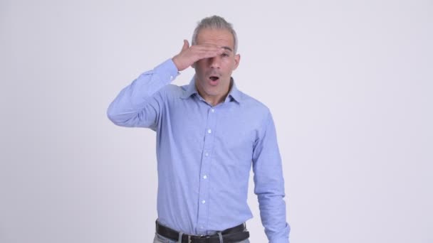 Stressed Persian businessman covering eyes against white background — Stock Video