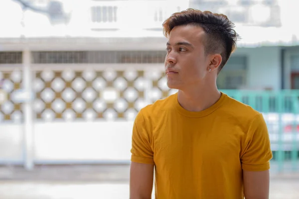 Jovem homem asiático pensando e olhando para longe nas ruas ao ar livre — Fotografia de Stock