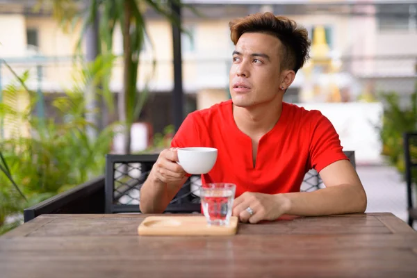 Joven hombre asiático pensando en la cafetería al aire libre —  Fotos de Stock