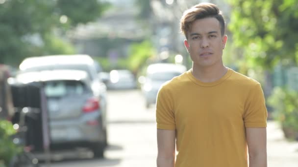 Feliz joven asiático hombre sonriendo con los brazos cruzados al aire libre — Vídeos de Stock