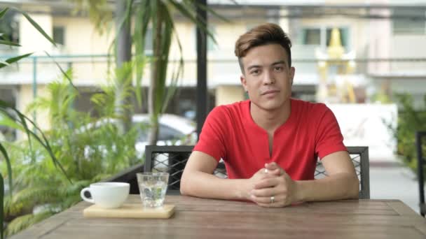 Felice giovane asiatico uomo sorridente alla caffetteria all'aperto — Video Stock