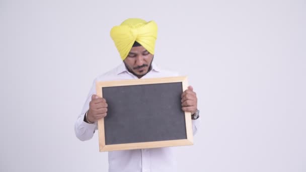 Happy bearded Indian Sikh businessman holding blackboard — Stock Video