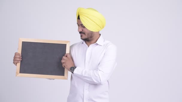 Feliz barbudo indiano Sikh empresário segurando quadro-negro e dando polegares para cima — Vídeo de Stock