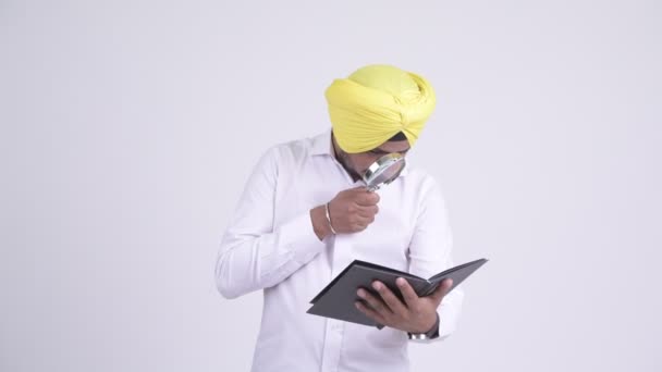 Barbudo indio Sikh hombre de negocios libro de lectura con lupa — Vídeo de stock