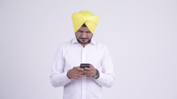 Un om de afaceri indian cu barbă fericită gândește în timp ce folosește telefonul — Videoclip de stoc