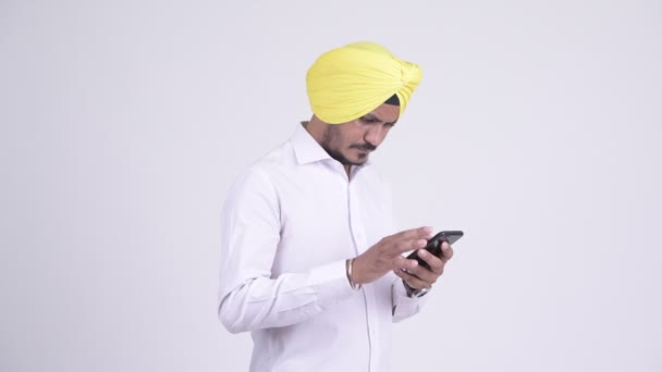 Feliz barbudo indio Sikh empresario usando el teléfono y recibiendo buenas noticias — Vídeo de stock