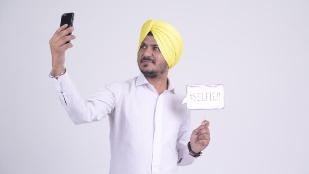 Счастливый бородатый индийский сикх бизнесмен делает селфи с бумажной вывеской — стоковое видео