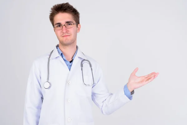 Jovem médico bonito com óculos mostrando algo — Fotografia de Stock