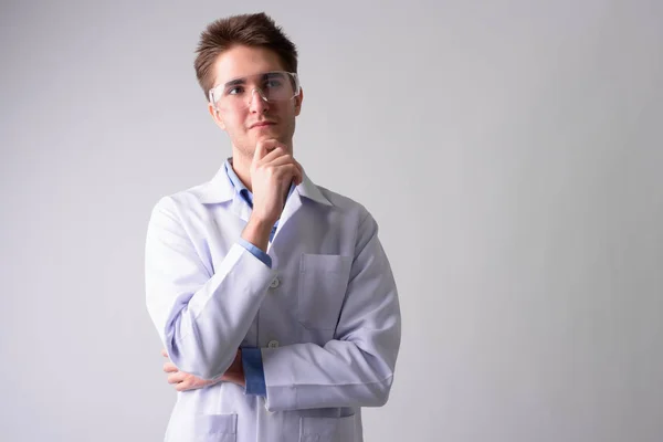 Young handsome man doctor with protective glasses thinking — Stock Photo, Image