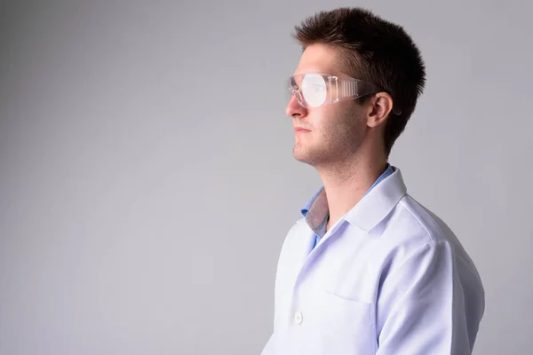 Profile view of young handsome man doctor with protective glasses — Stock Photo, Image