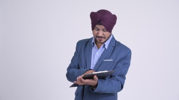 Szakállas indiai szikh üzletember olvasásakor a csipeszes írótábla beszél — Stock videók