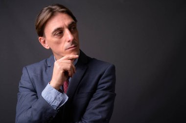 Olgun yakışıklı İtalyan işadamı gri arka plan üzerinde düşünme