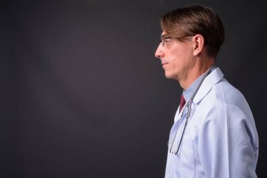 Olgun İtalyan yakışıklı Doktor gri arka plan profil görünümü