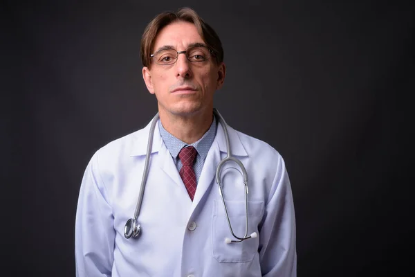 Reif hübsch italienisch mann doktor vor grauem hintergrund — Stockfoto