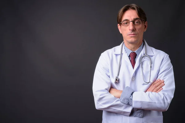 Volwassen knap italiaans man arts tegen grijs achtergrond — Stockfoto