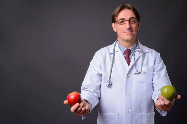 Чоловік лікар тримає зелене яблуко і червоне яблуко — стокове фото