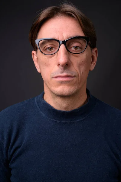 Face of mature handsome Italian man against gray background