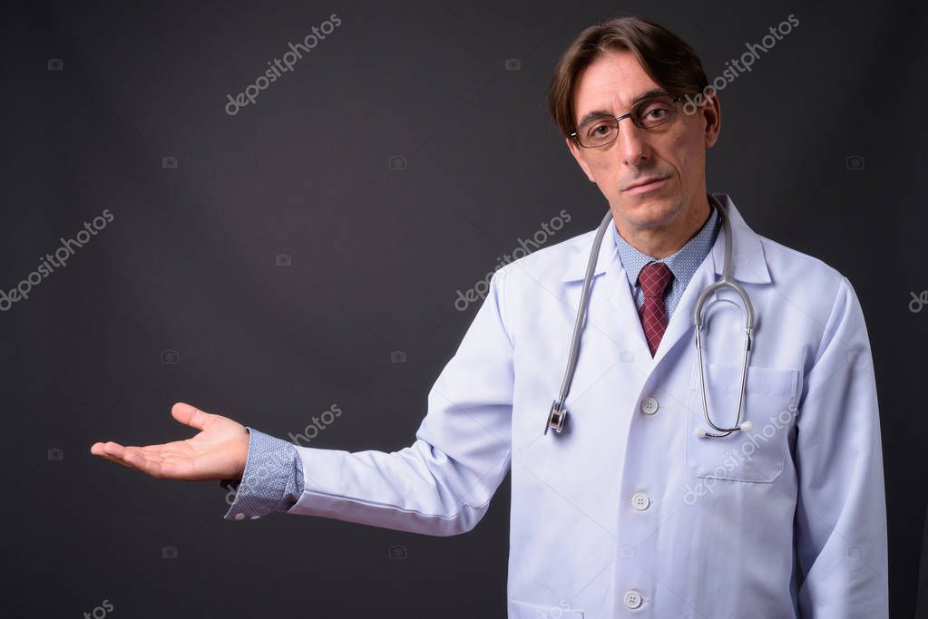 Male Doctor Looking At Clipboard Against White Background