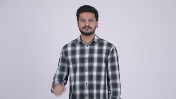 Portrait of young happy bearded Indian man pointing up — Stock video