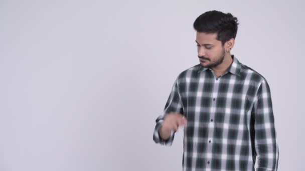 Портрет молодого счастливого бородатого индийца, щёлкающего пальцами и показывающего что-то — стоковое видео