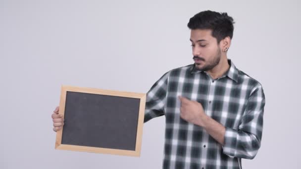 Young happy bearded Indian man with blackboard and giving thumbs up