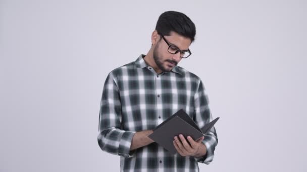 Jeune homme indien barbu heureux lecture livre avec des lunettes — Video