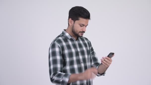 Jovem homem indiano barbudo feliz usando telefone e recebendo boas notícias — Vídeo de Stock