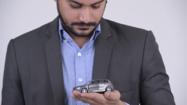 Giovane felice barbuto uomo d'affari indiano in possesso di auto giocattolo — Video Stock