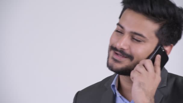 Молодой счастливый бородатый индийский бизнесмен разговаривает по телефону — стоковое видео