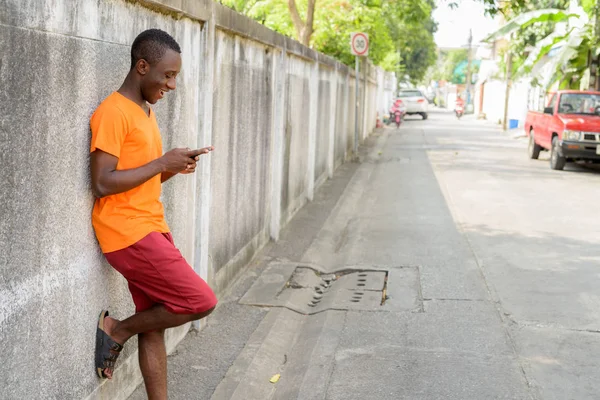 Προβολή προφίλ των γραπτών μηνυμάτων ευτυχισμένη μαύρη αφρικανική νεαρός με το τηλέφωνο — Φωτογραφία Αρχείου