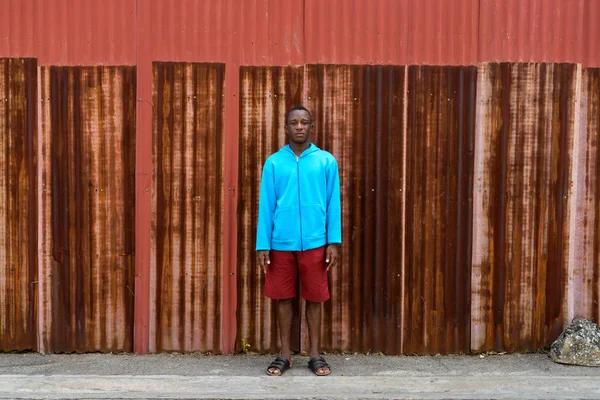Νεαρός μαύρος Αφρικανός στέκεται στον παλιό σκουριασμένο τοίχο. — Φωτογραφία Αρχείου