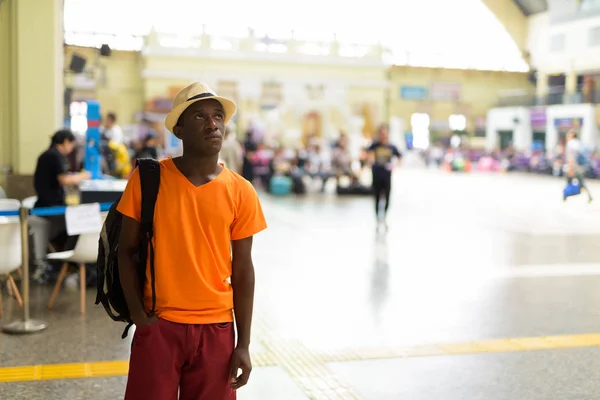 Αφρικής Τουριστική άνδρα χαμογελώντας ενώ σκέψης στο σιδηροδρομικό σταθμό — Φωτογραφία Αρχείου