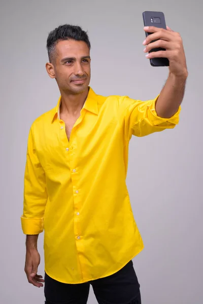 Jeune homme d'affaires persan heureux avec chemise jaune prendre selfie — Photo